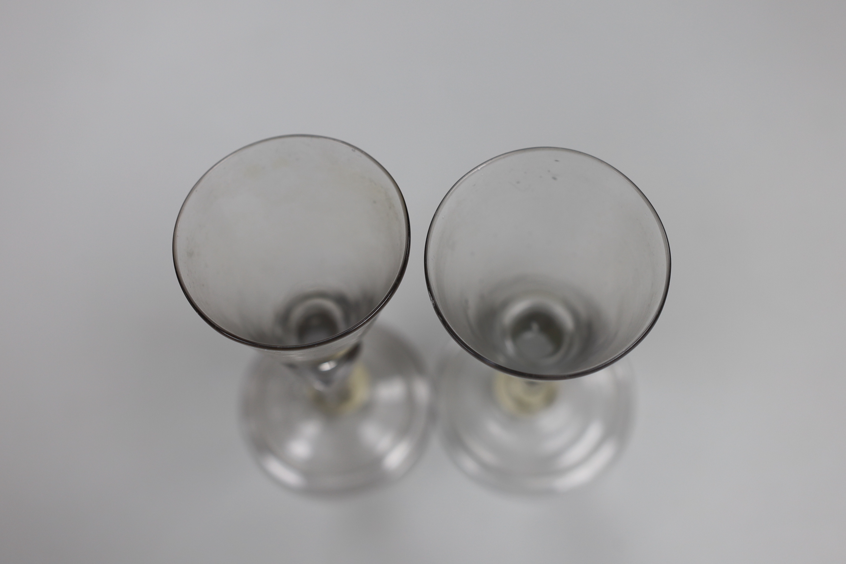 A pair of Continental facon de Venice wine glasses, first half 18th century, round funnel bowls and hollow moulded pedestal stems, folded feet, tallest 13.5cm